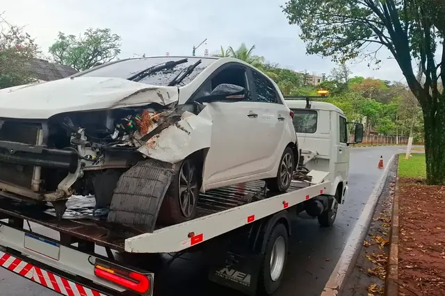 Carro branco batido sendo removido pelo guincho plataforma após um acidente